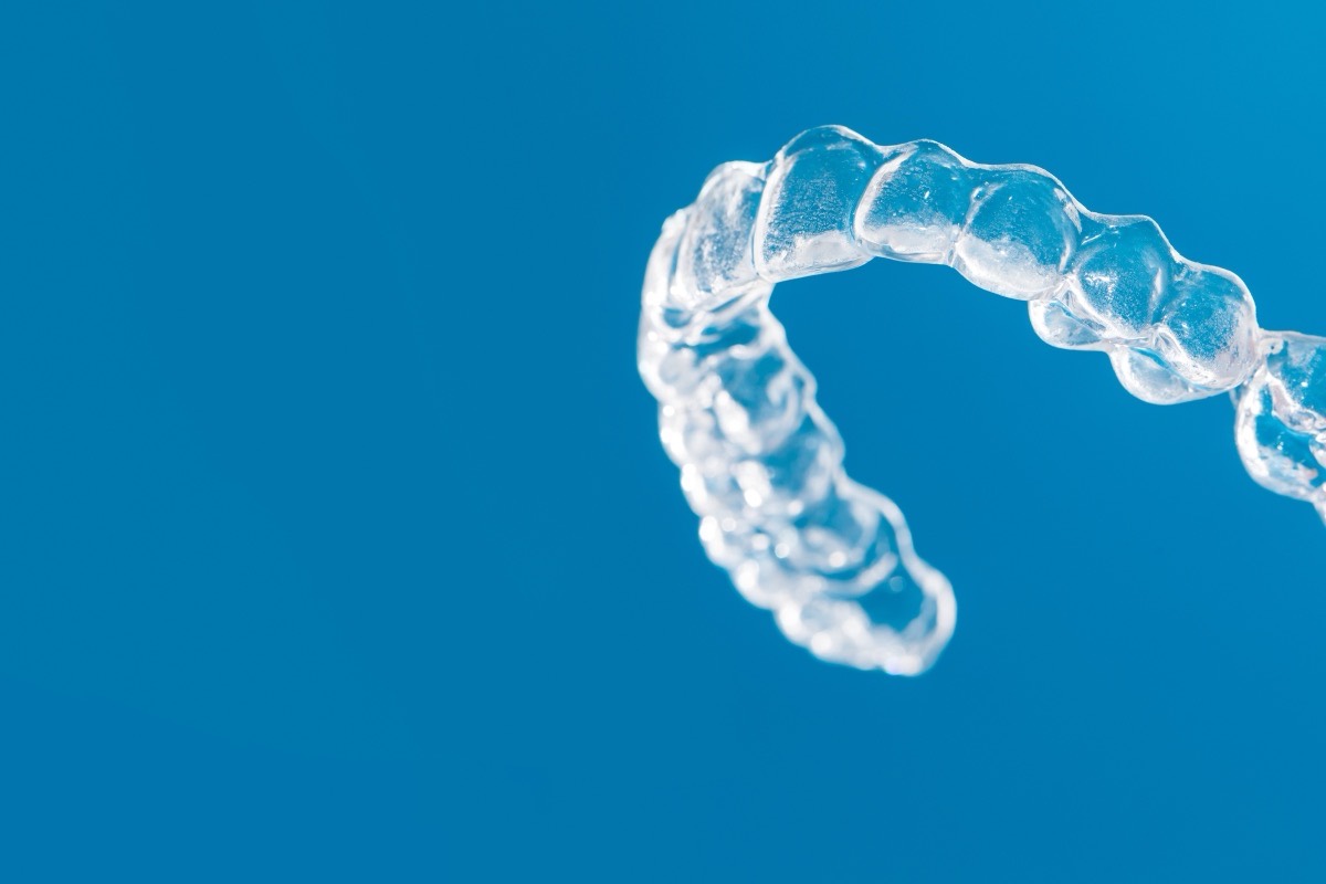 Clear dental aligner on a blue background